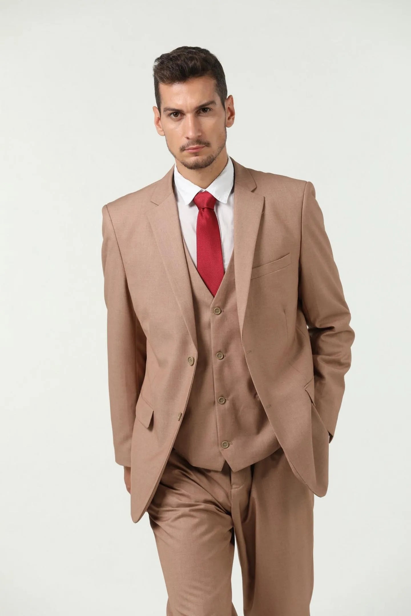 close-up of model wearing a champagne colored men's slim fit two-button 3-piece suit with red tie, showing suit jacket details.