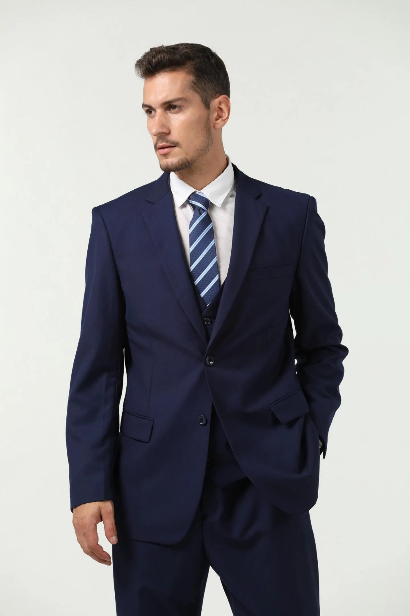 model in navy blue slim fit 3-piece suit, adjusting jacket lapel, showcasing the tailored fit and elegance.