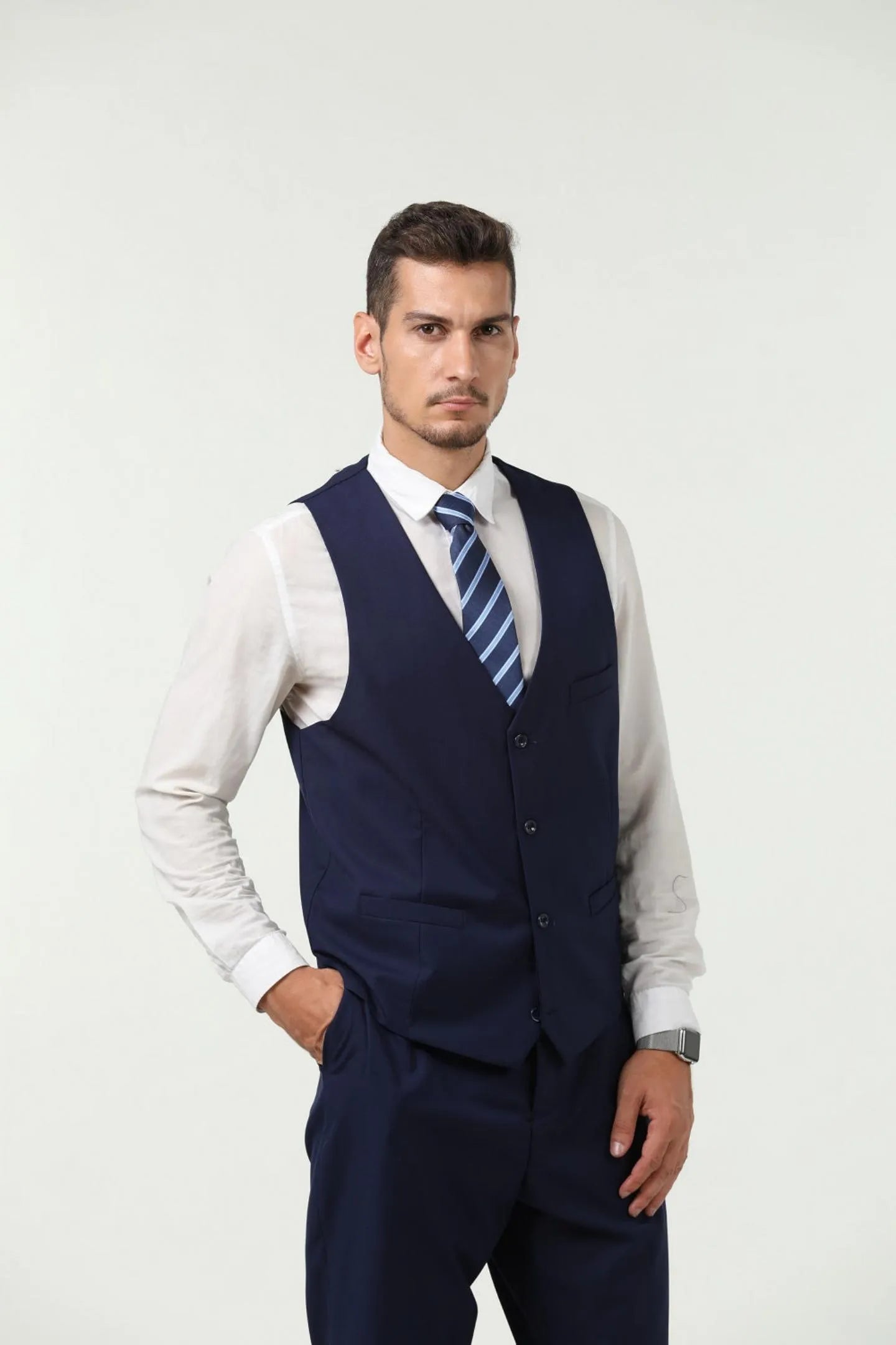 model in navy blue two-button 3-piece suit, looking confident, with a blue striped tie and tailored business wear.