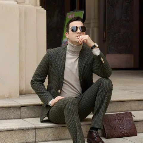 Sophisticated man in a charcoal pinstripe two-piece suit and turtleneck sitting on stone steps, showcasing modern men’s formalwear.