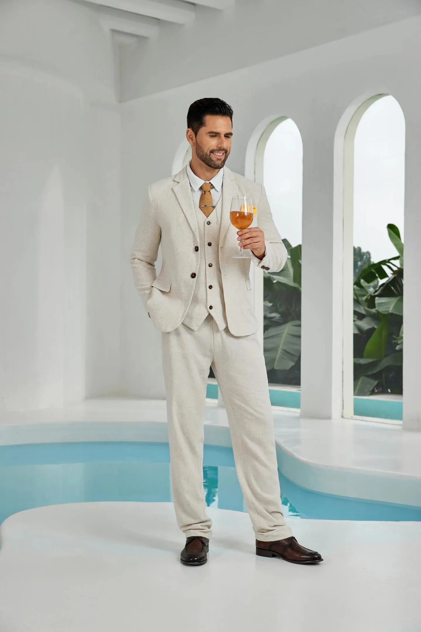 beige linen 3 piece suit for men – summer beach wedding outfit with blazer, vest, pants and cocktail glass in hand