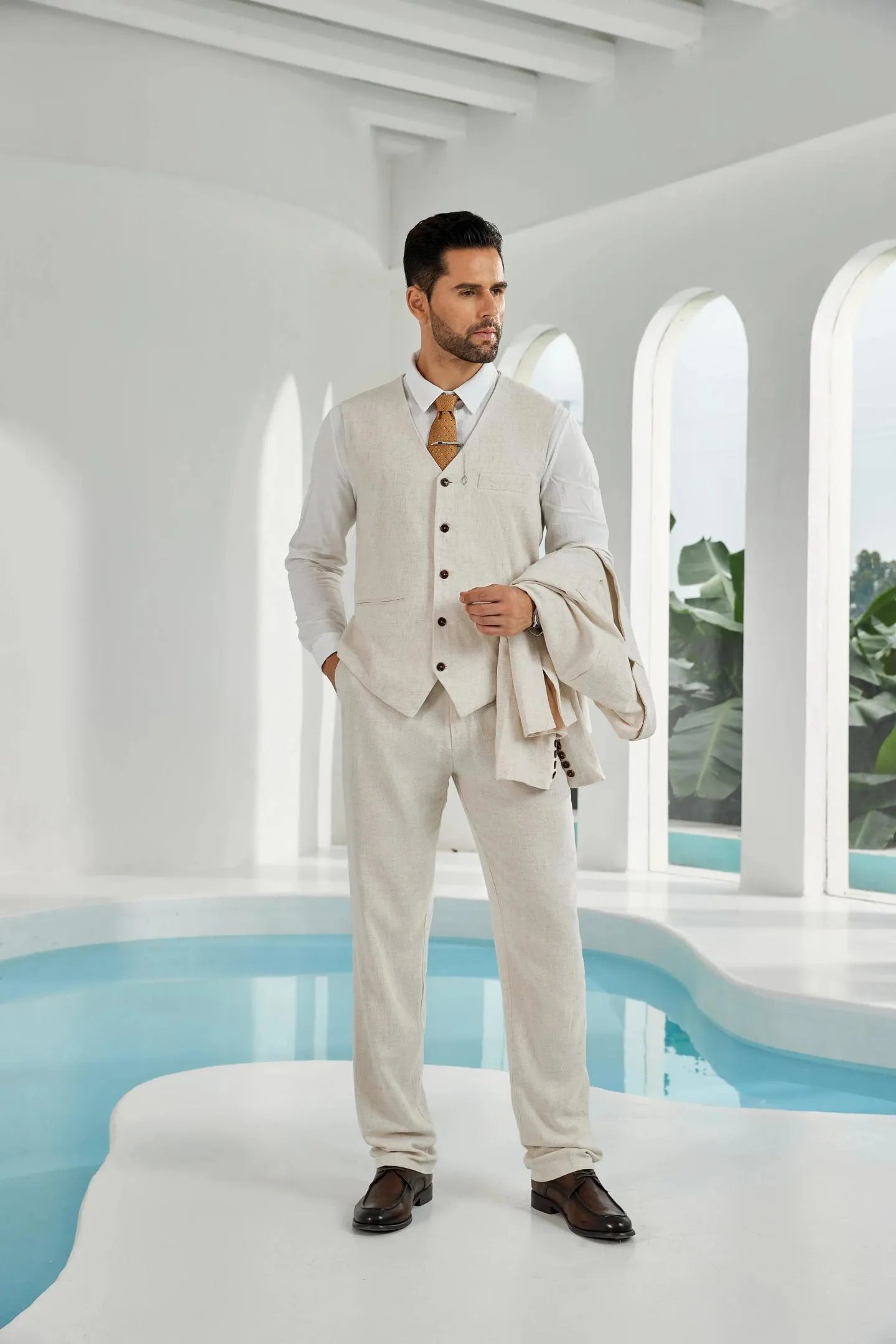 beige linen 2 piece suit for men – summer beach wedding style with vest, pants, and matching jacket carried in hand
