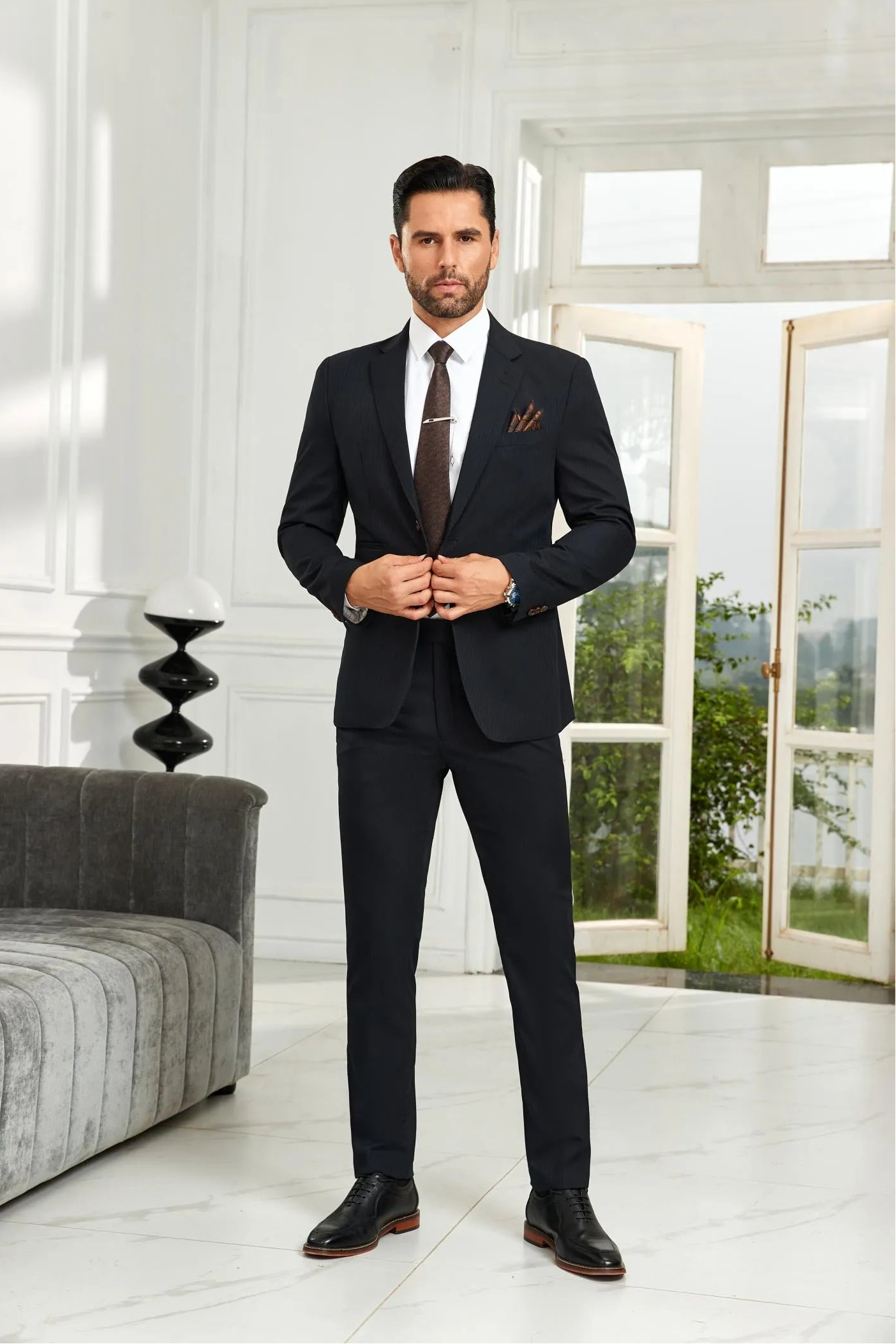 Model wearing black striped 2 piece men's suit with tailored blazer and trousers, styled with white shirt and brown tie in business formal look