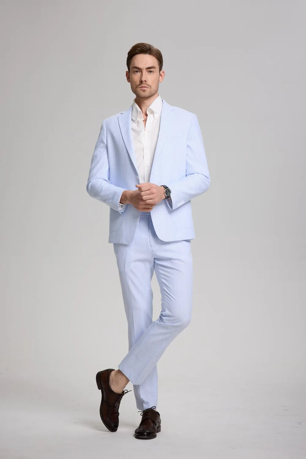Full-body view of man in blue striped seersucker suit with white shirt and brown shoes