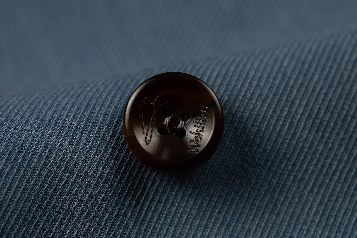 Men's blue double breasted blazer button detail - brown horn button with engraved logo on textured fabric