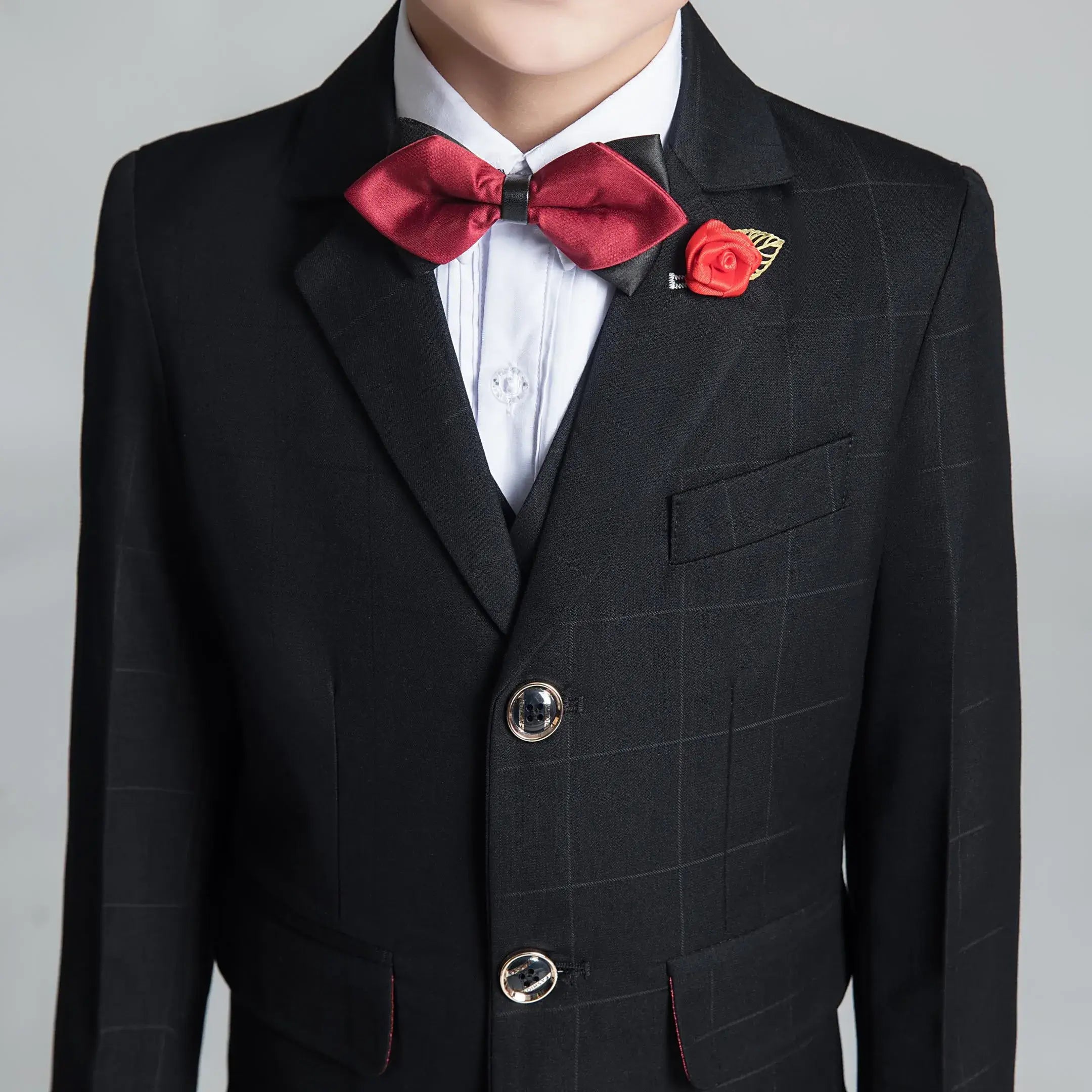 Detail shot of boys' black plaid blazer with red accents and decorative buttons