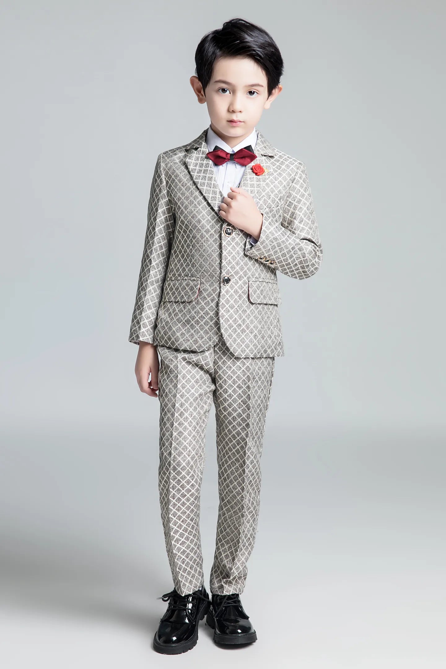 Stylish boys' diamond-printed suit with red bow tie and rose pin, ideal for weddings and formal celebrations