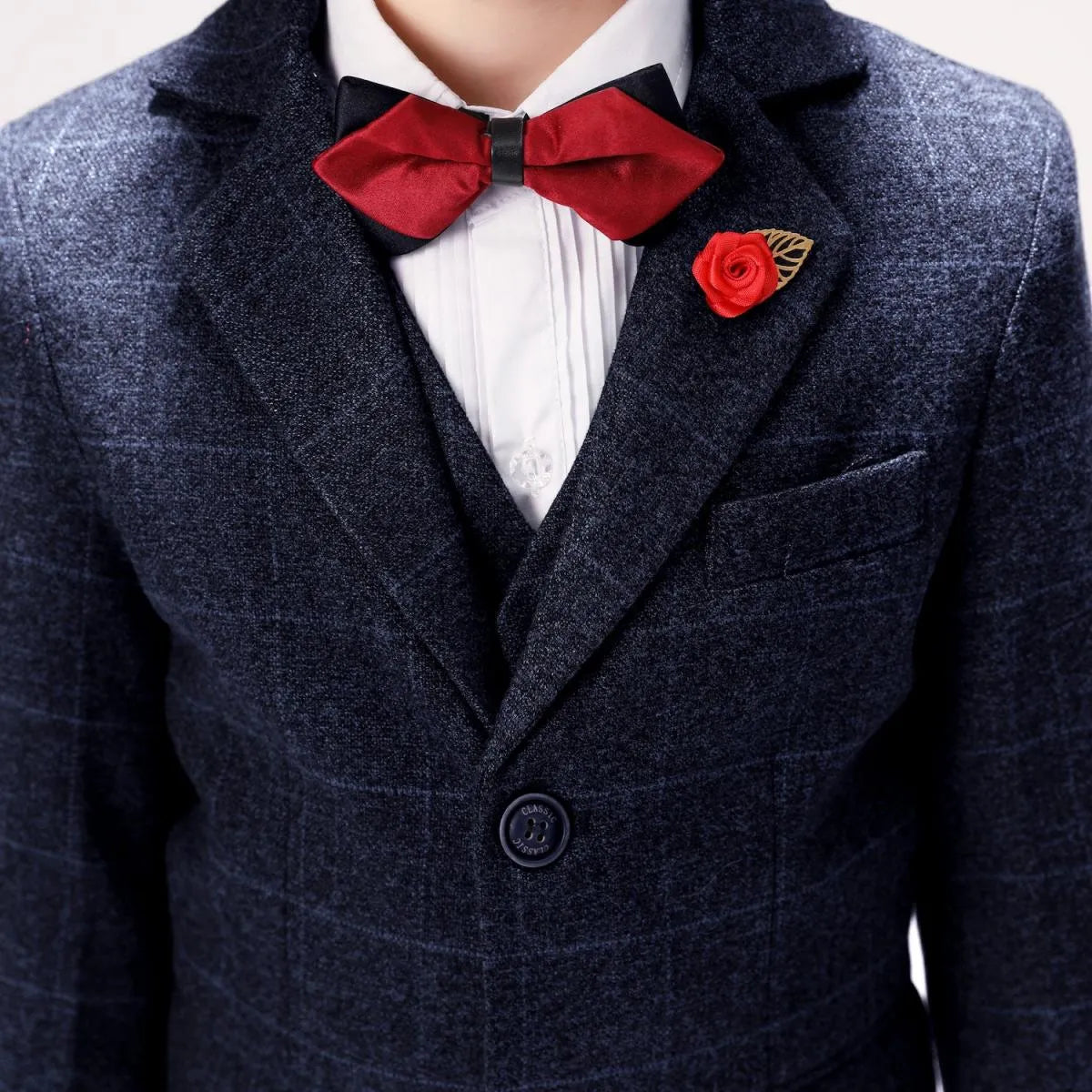 Close-up of plaid boys' prom suit jacket with red bow tie and rose lapel pin, elegant formalwear detail