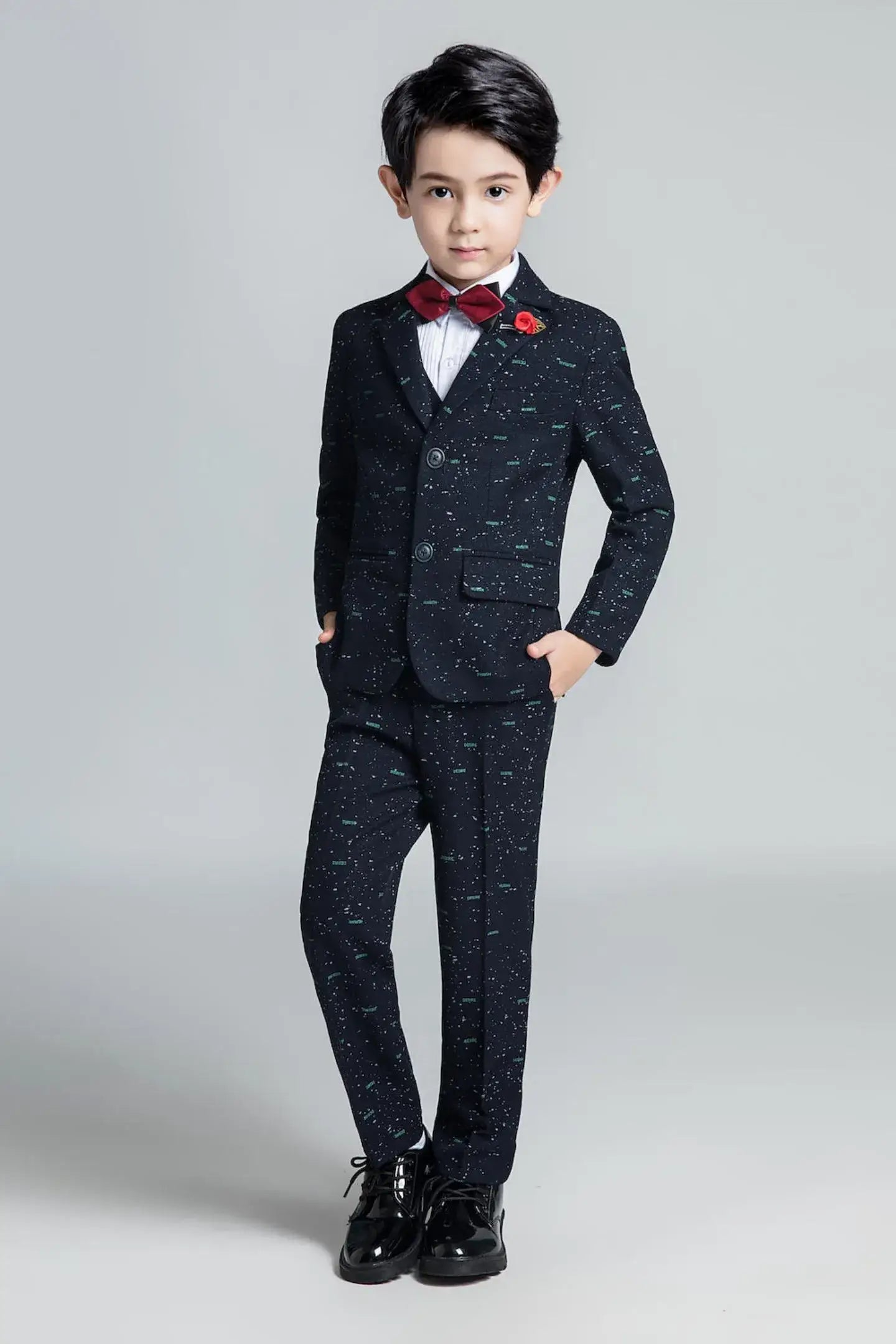 Boys' slim fit party suit with modern printed fabric, paired with red bow tie and formal shoes for stylish occasions