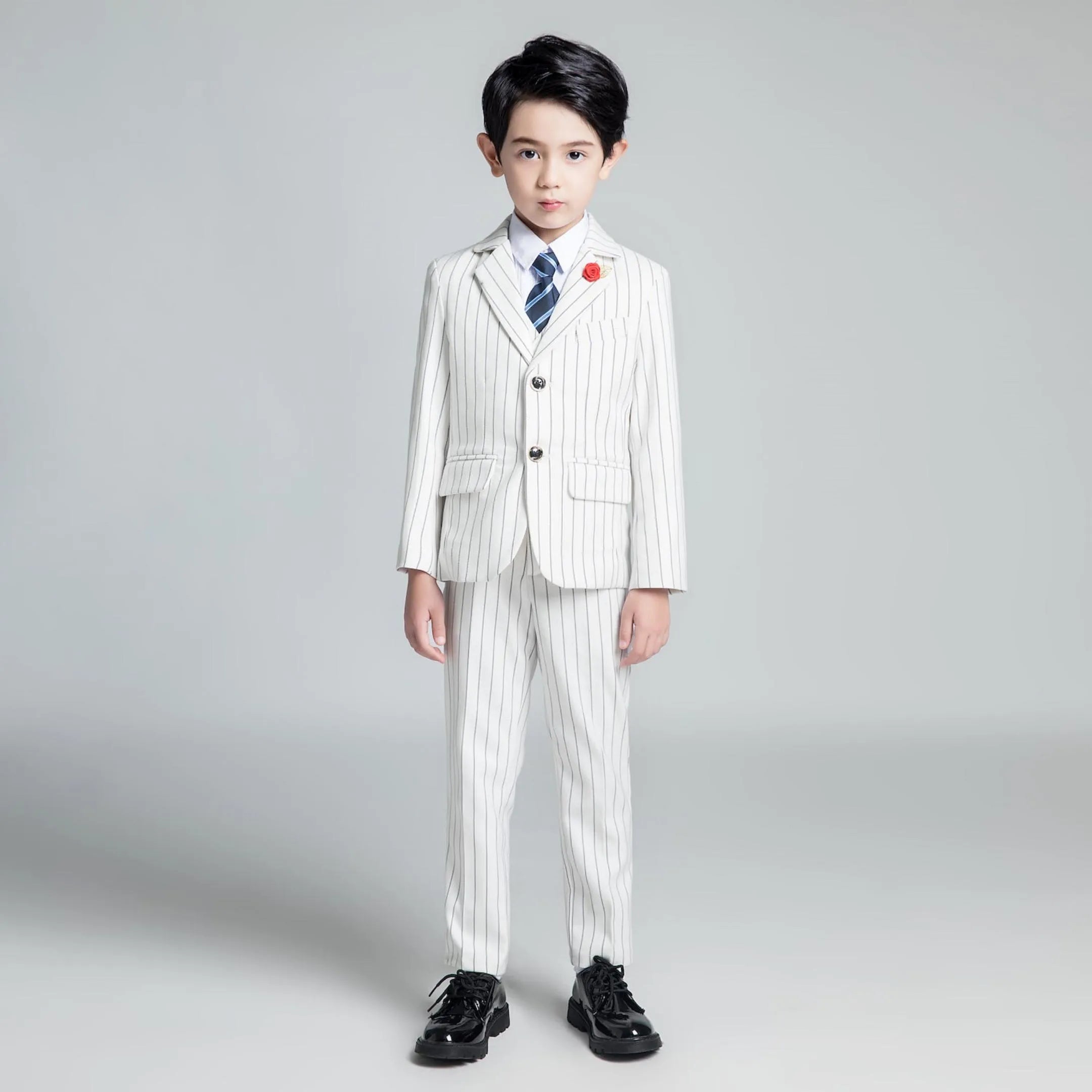 White striped boys formal suit with blue tie and red flower lapel pin