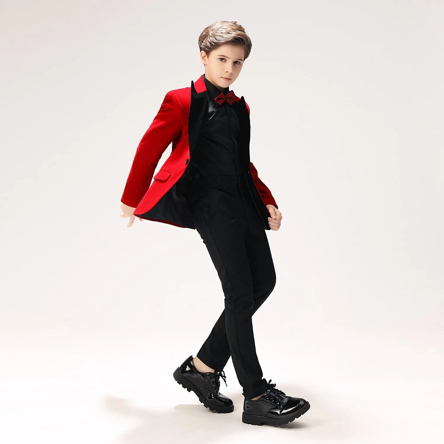 Boys' red velvet formal outfit with black trousers and bow tie – motion pose for events