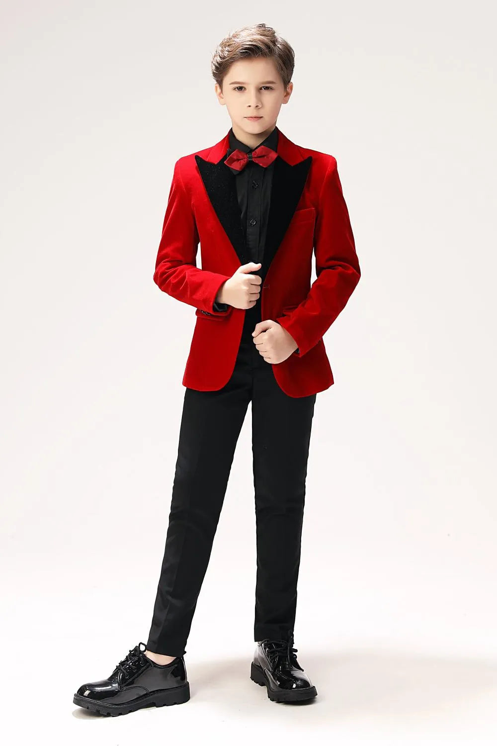 Red velvet boys' tuxedo with black lapel, styled with black shirt and red bow tie – front view