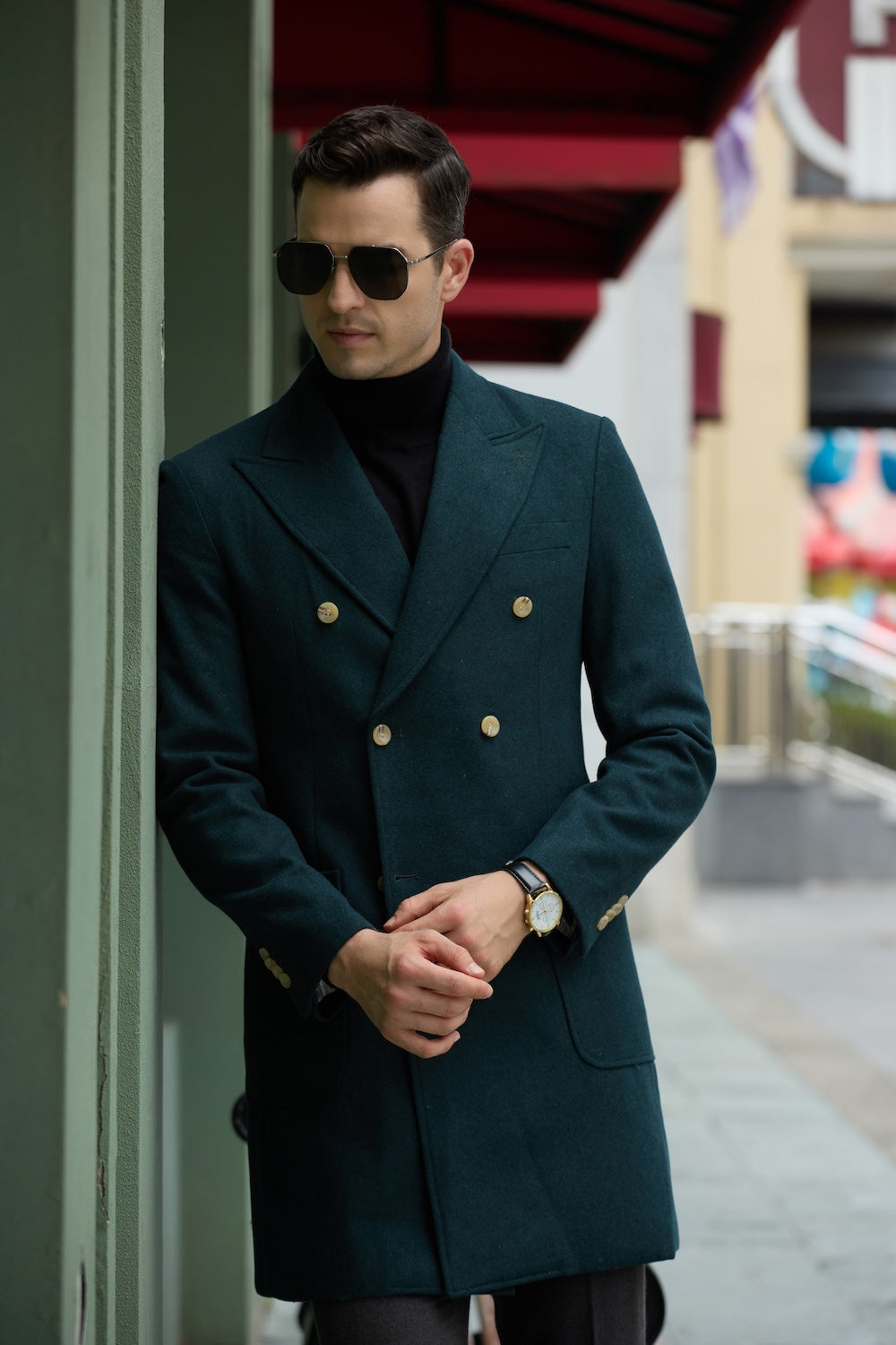 Men's green wool overcoat -  double breasted long winter coat with gold buttons, standing by wall in urban street scene