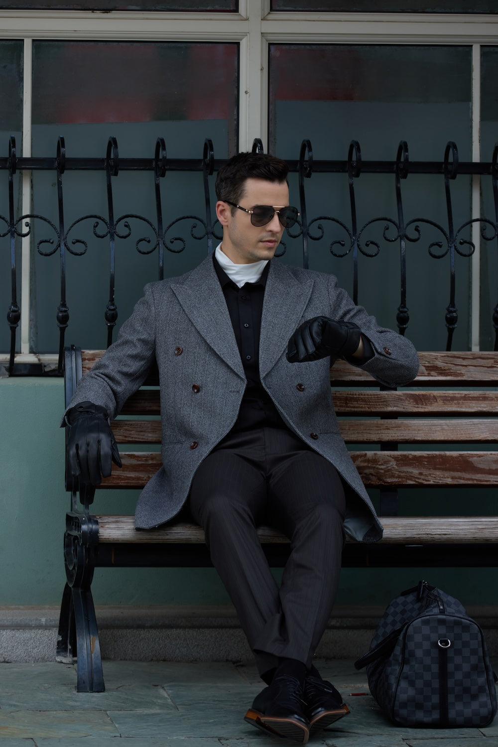 Men's gray wool overcoat - urban double breasted long winter coat, formal casual outerwear with leather gloves sitting on bench in city scene
