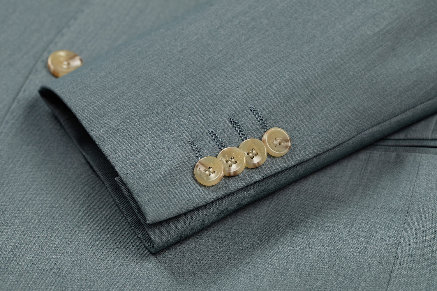 Men's sage green blazer cuff detail - horn buttons with stitched seam on formal wedding jacket sleeve