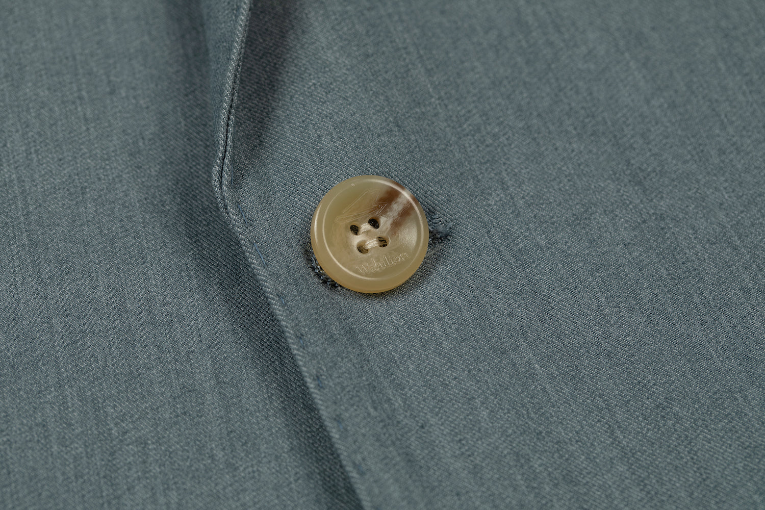 Men's sage green blazer detail - horn button with stitched seam on formal wedding jacket fabric