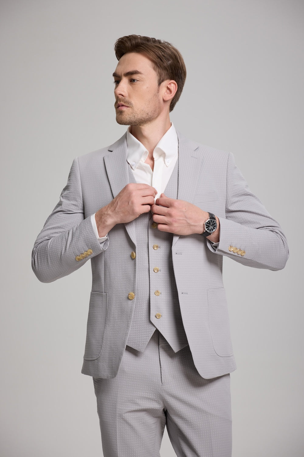Close-up of grey seersucker blazer and vest with tan buttons and textured fabric