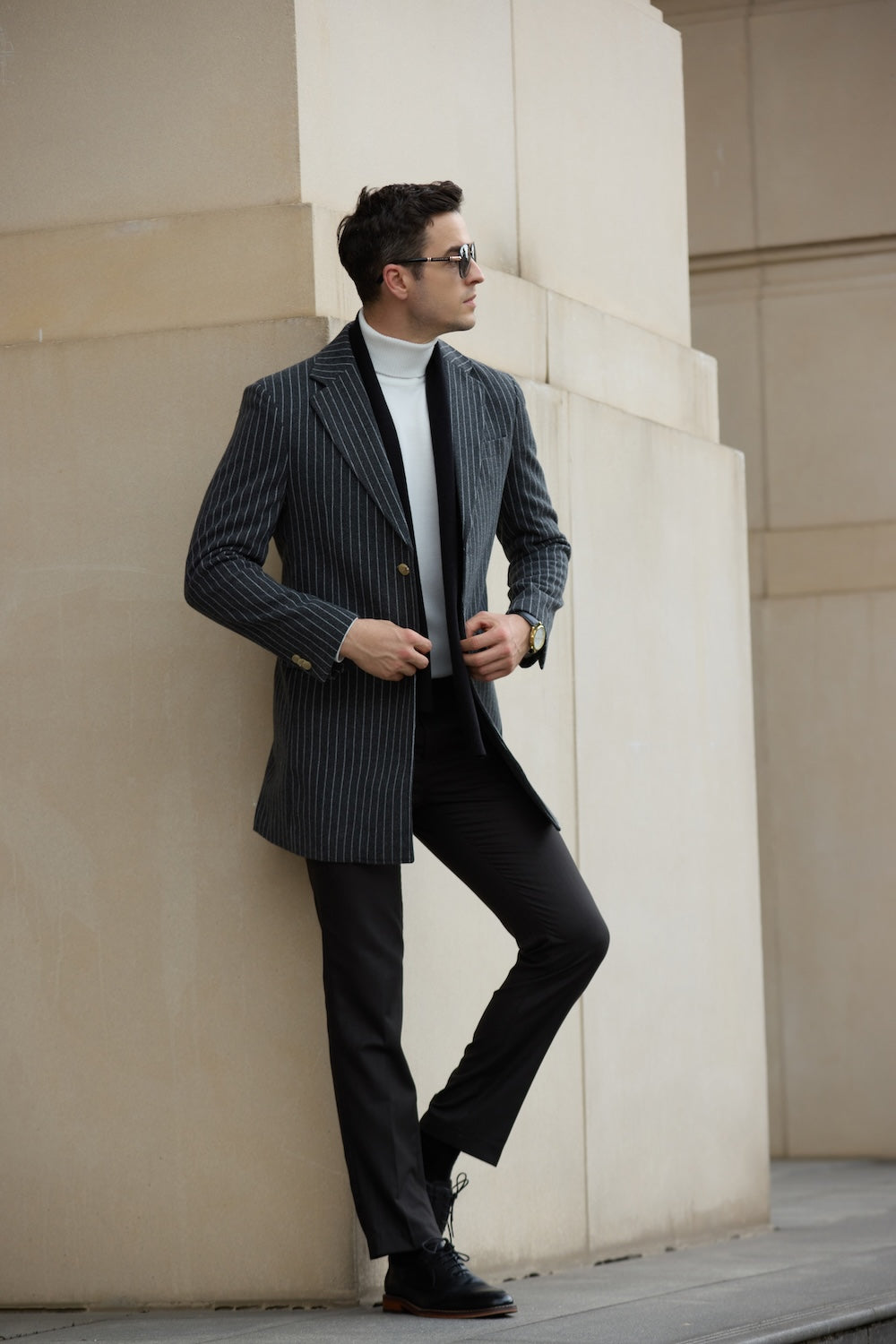 Men’s long winter coat in grey – leaning pose with pinstripe design and gold buttons