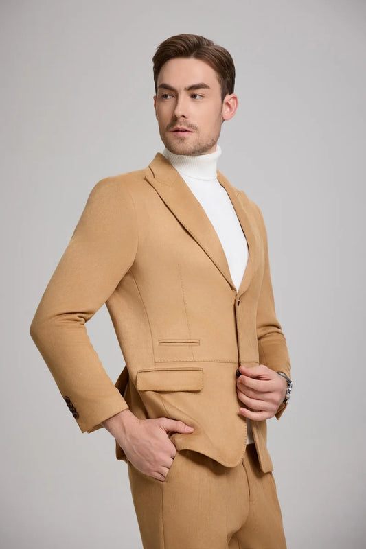 side view of a man adjusting his light brown suede blazer, showcasing a peak lapel style.