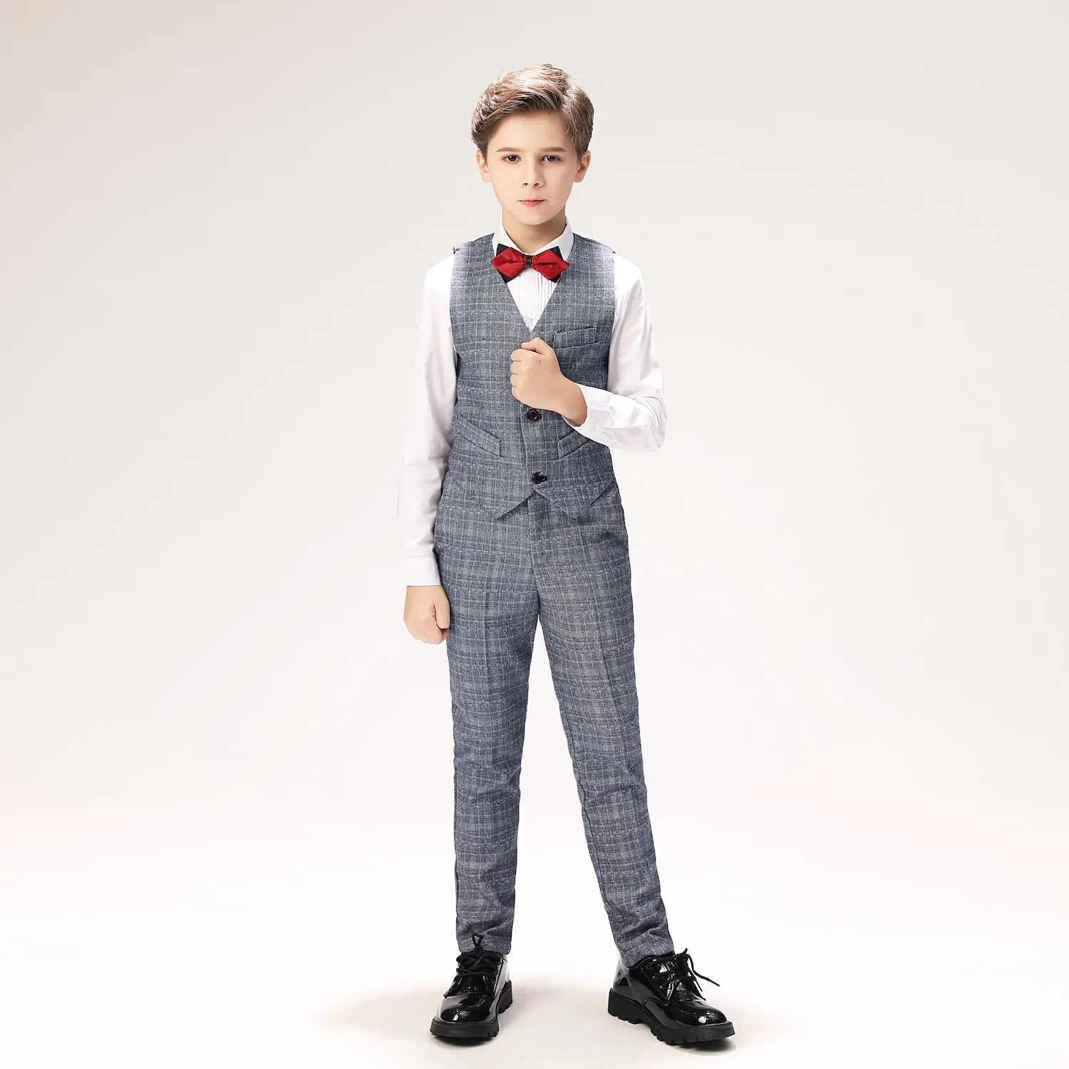 Vest-focused pose with grey plaid suit trousers and red bow tie for boys formalwear collection