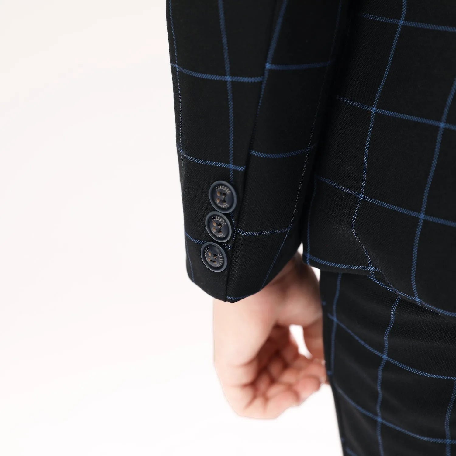 Sleeve button close-up on boys plaid wedding blazer with three-button detail