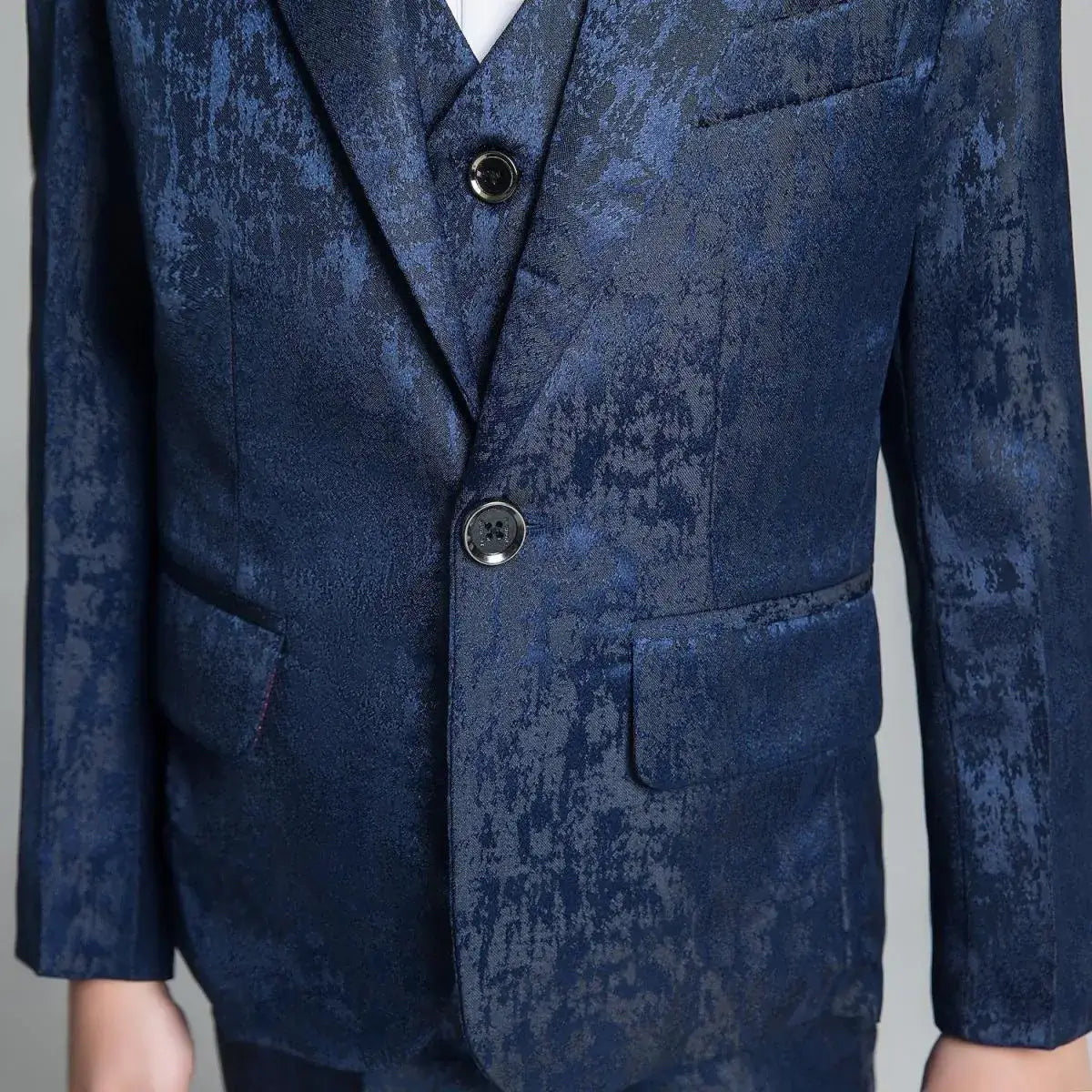 Detailed view of boys' navy slim fit suit with textured floral pattern and single-breasted button closure