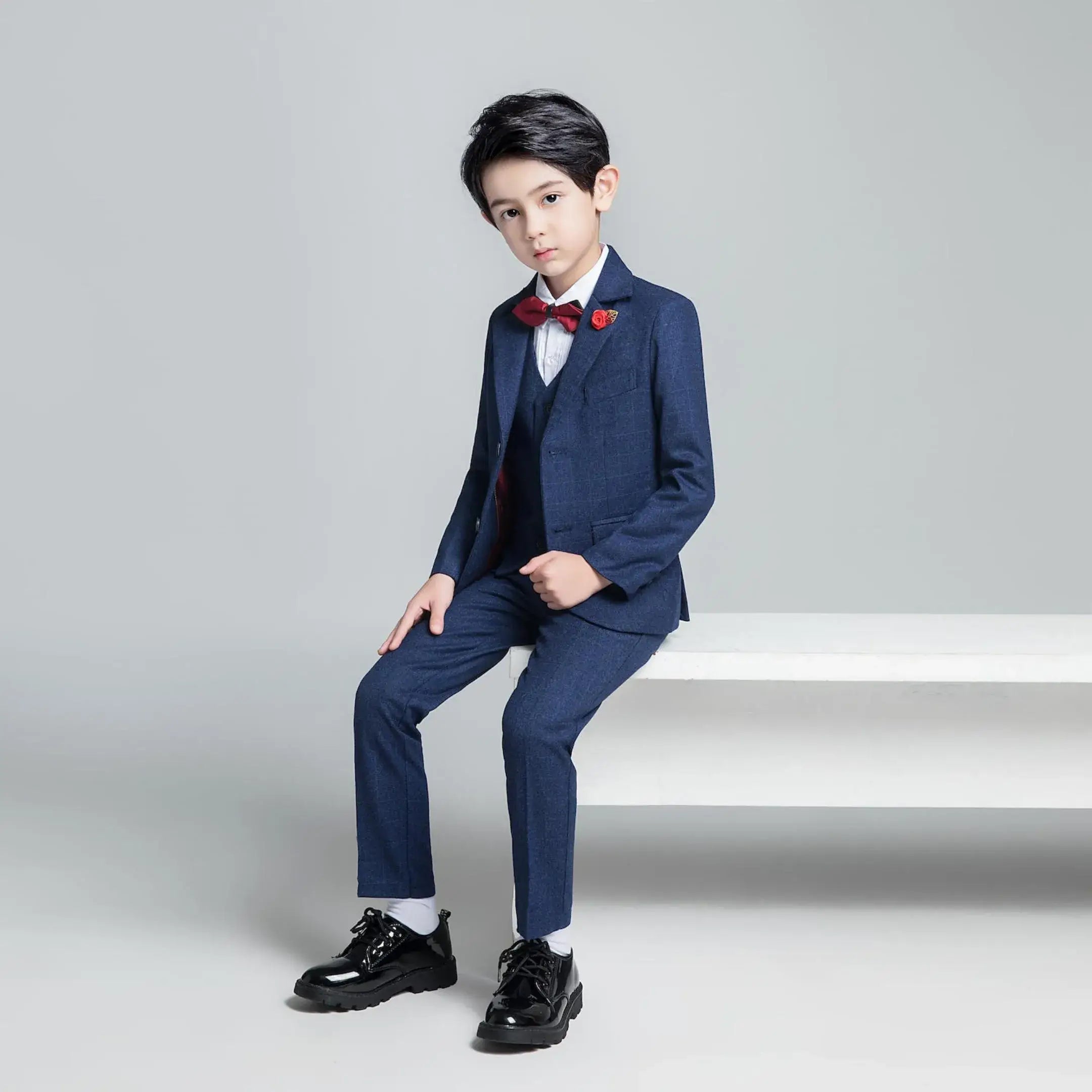 Full-body view of boy in navy check suit and red accessories – formal boys wedding and party look