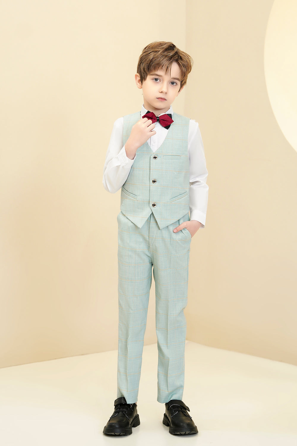 Boy wearing mint green plaid formal vest and pants with red bow tie for wedding or party