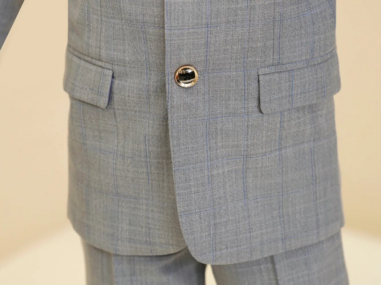 Light grey plaid boys suit: Close-up of button & checked blazer front detail