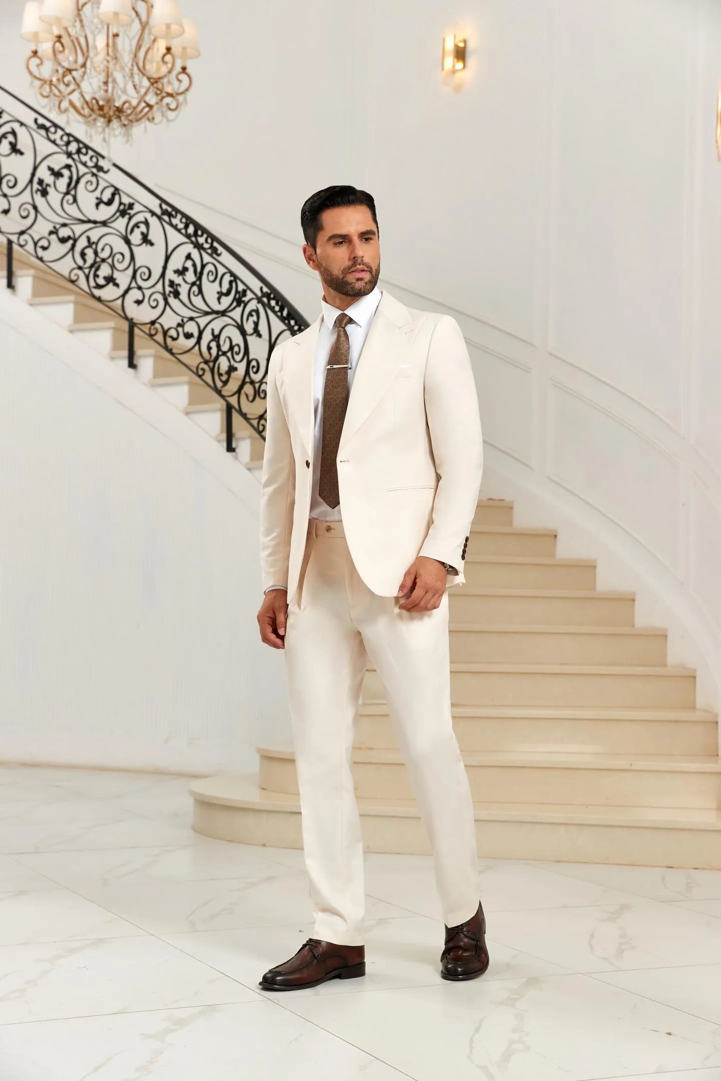 White 2 piece suit for men with peak lapel blazer and pants, full body view near staircase, wedding formal style.
