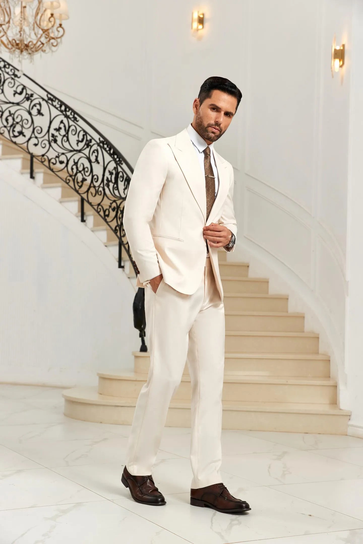 White 2 piece men's suit peak lapel blazer and trousers, side pose with hands in pocket, classic wedding look.