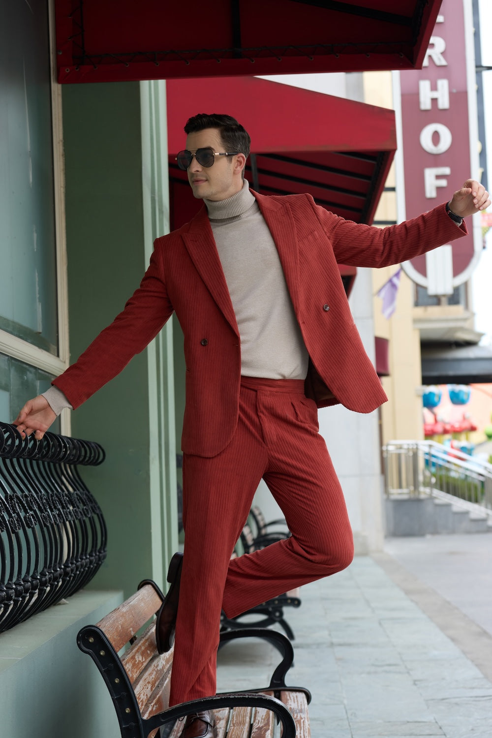Dynamic side pose in red corduroy suit – man leaning playfully with sunglasses
