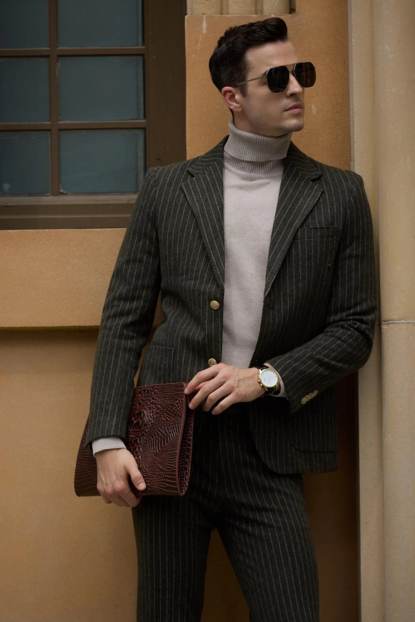 Man in a green herringbone pinstripe 2-piece suit, standing with hands in pockets, showcasing the full suit and stylish business attire.