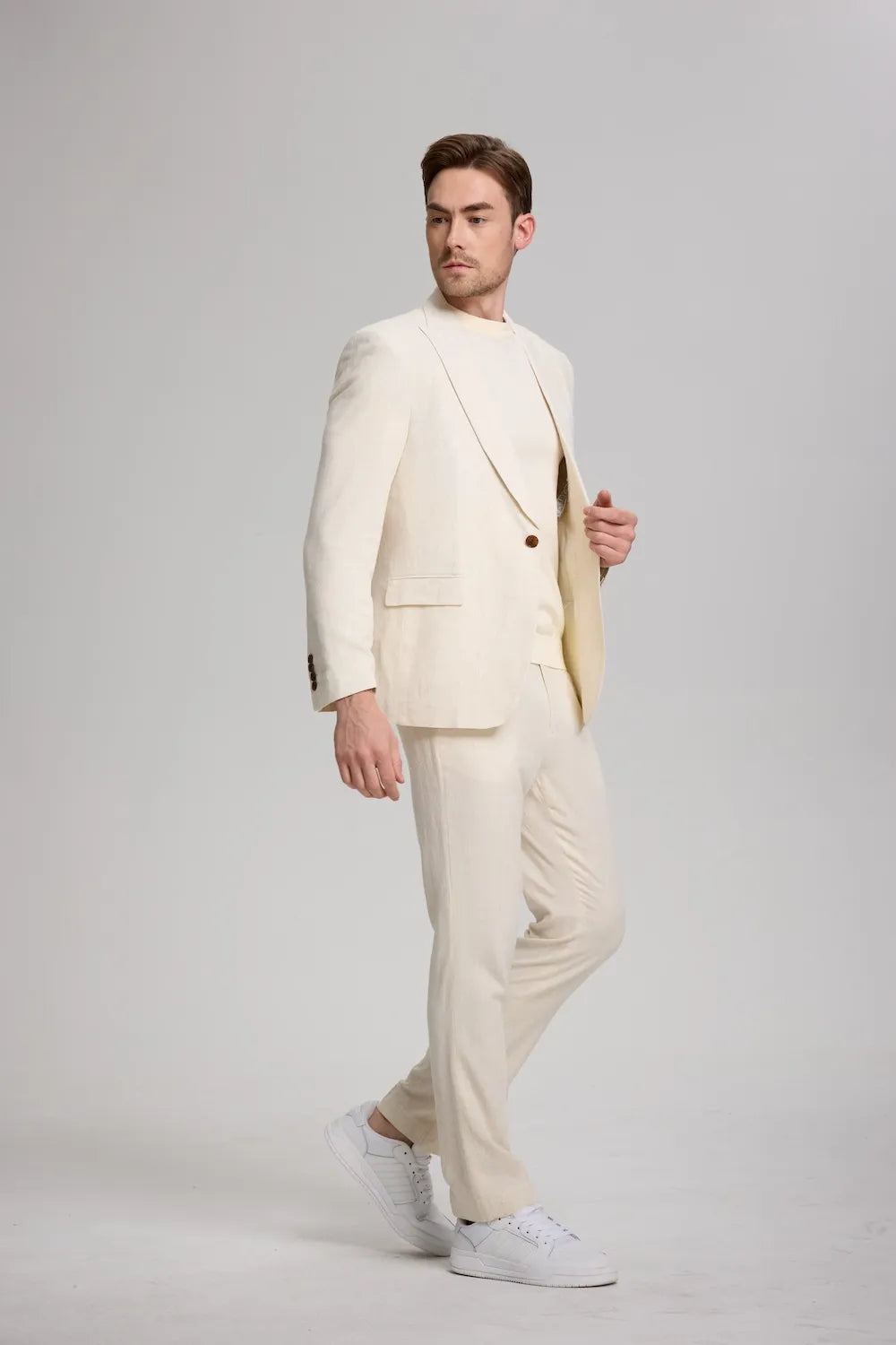Beige linen two-piece suit for men walking – casual summer look with sneakers and crew neck tee