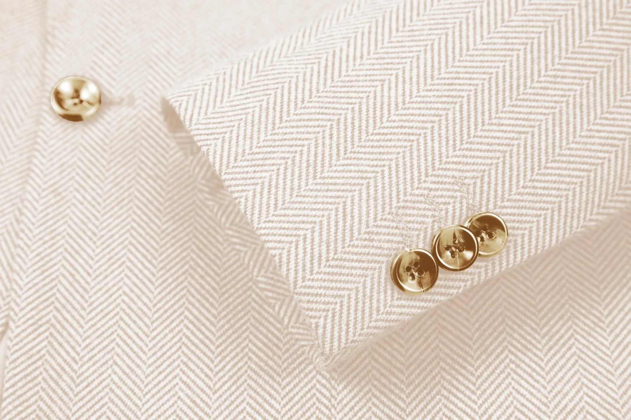 Detailed shot of men's beige herringbone business suit sleeve – highlighting fine tailoring of 2-piece suit