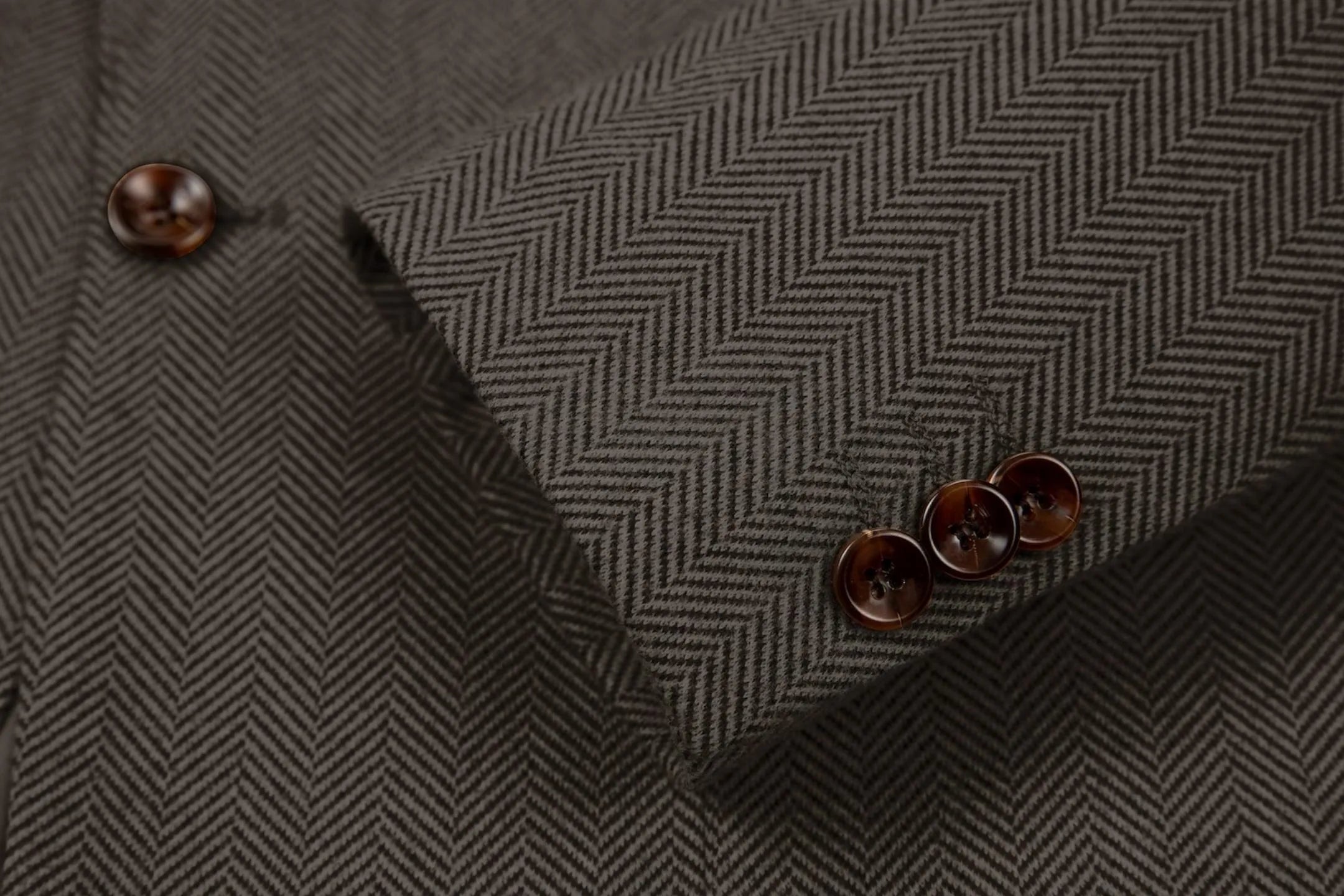 Detailed shot of men's black brown herringbone business suit sleeve – showcasing fine craftsmanship of the 2-piece suit