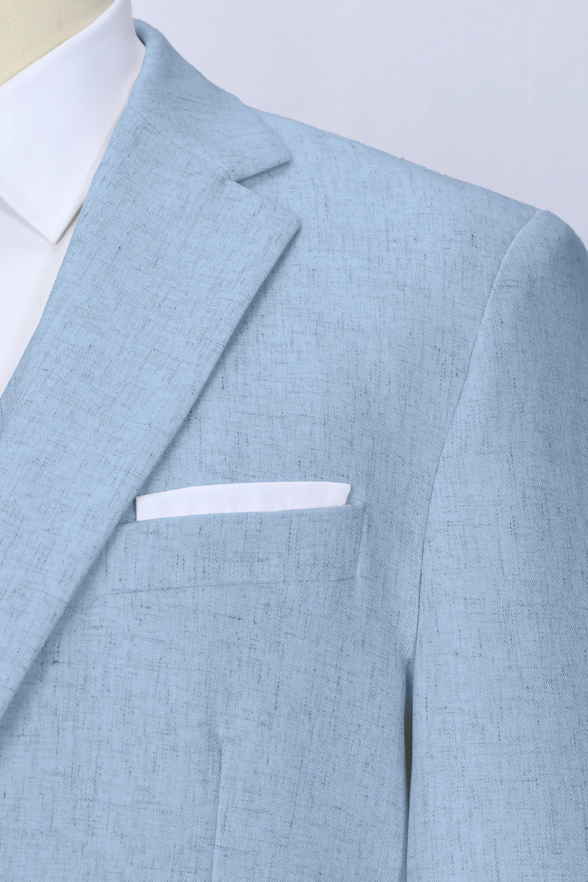 Close-up of light blue linen suit lapel and chest pocket – breathable summer fabric detail