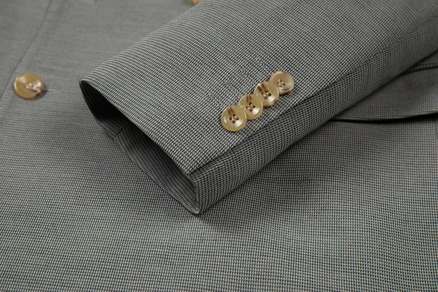 Close-up of blazer sleeve with gold buttons and fine plaid texture