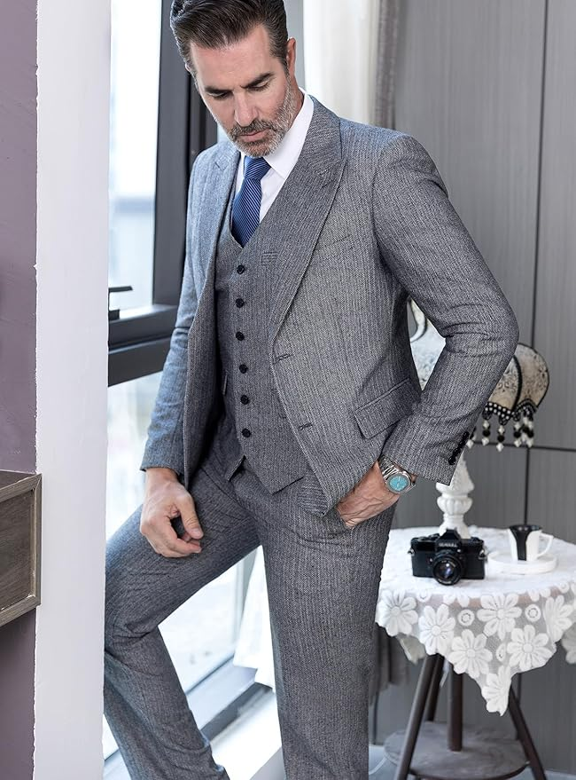 Close-up of grey herringbone wedding suit for men, featuring peak lapel blazer and buttoned vest in 3 piece set